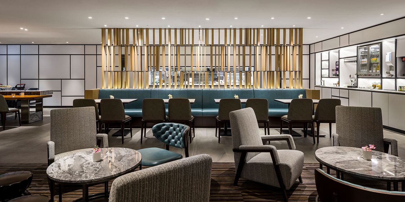 广东会集团接待大厅，暖金色灯光下的高端休憩空间，礼宾人员正在为来访嘉宾提供签到与引导服务。